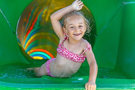 Niña sonriente en tobogán acuático colorido en el camping CAPFUN Madrague en PORNIC (44).