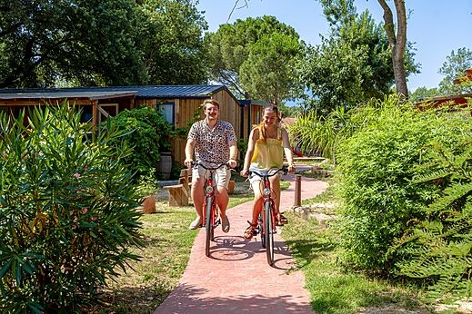 Pareja sonriente en bicicleta por camino del camping CAPFUN Mael en ARGELES.