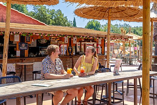 Pareja sonriente con cócteles en el bar-restaurante del camping CAPFUN Mael en ARGELES SUR MER (66).