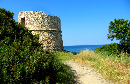 Torre de piedra hist�rica junto al mar, sendero de tierra en C�rcega.