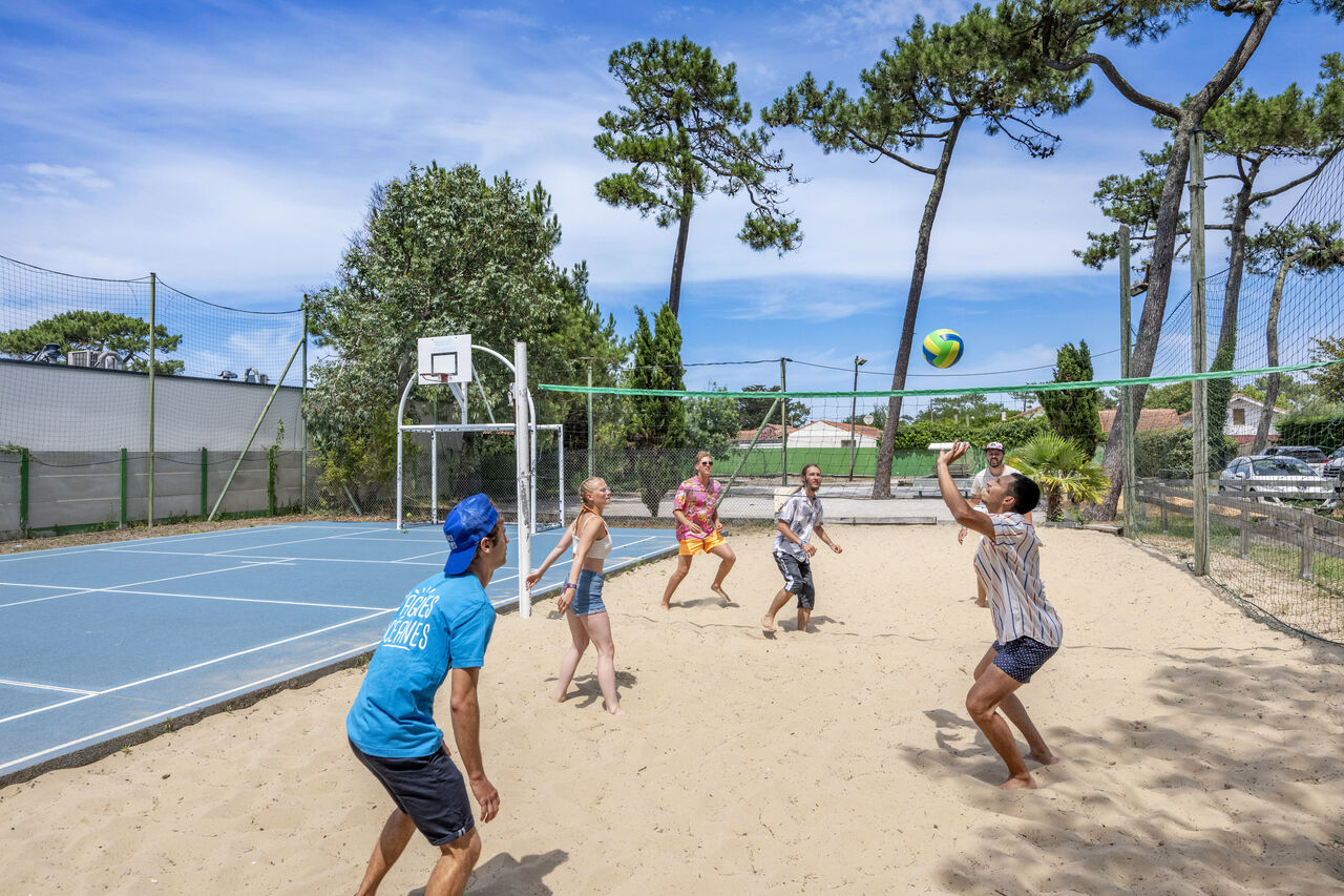 Cancha de voleibol de playa con jugadores en el camping VAGUES OCEANES Marina Landes, Mimizan.