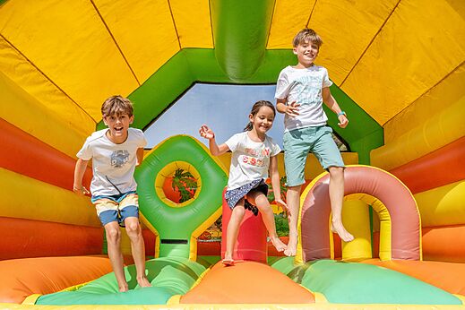 Ni�os divirti�ndose en juegos inflables coloridos en el camping VAGUES OCEANES Marina Landes.