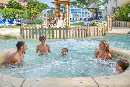 Familia feliz en el jacuzzi de la piscina en el camping VAGUES OCEANES Marina Landes.