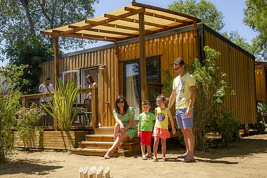 Familia jugando frente a un Mobil-home moderno con terraza en el camping VAGUES OCEANES Marinette en Ste Marie La Mer (66).
