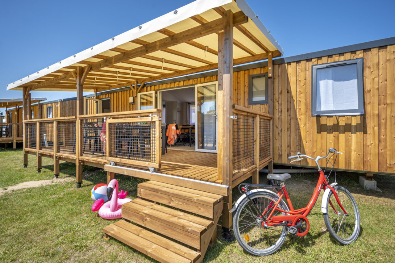 Mobil-home de madera con terraza, bicicleta roja en el camping CAPFUN Mer en Labenne-Oc�an (40).