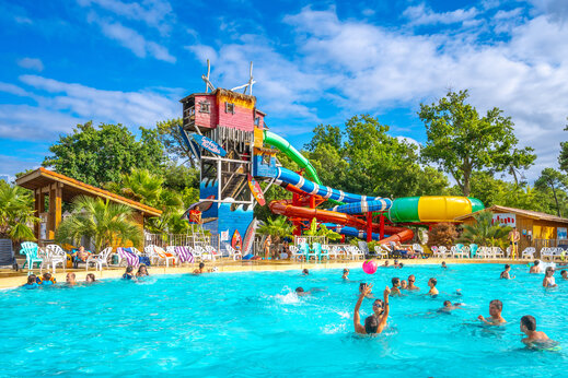 Piscina exterior y toboganes acu�ticos con sillas en el camping CAPFUN Mer en Labenne-Oc�an (40).