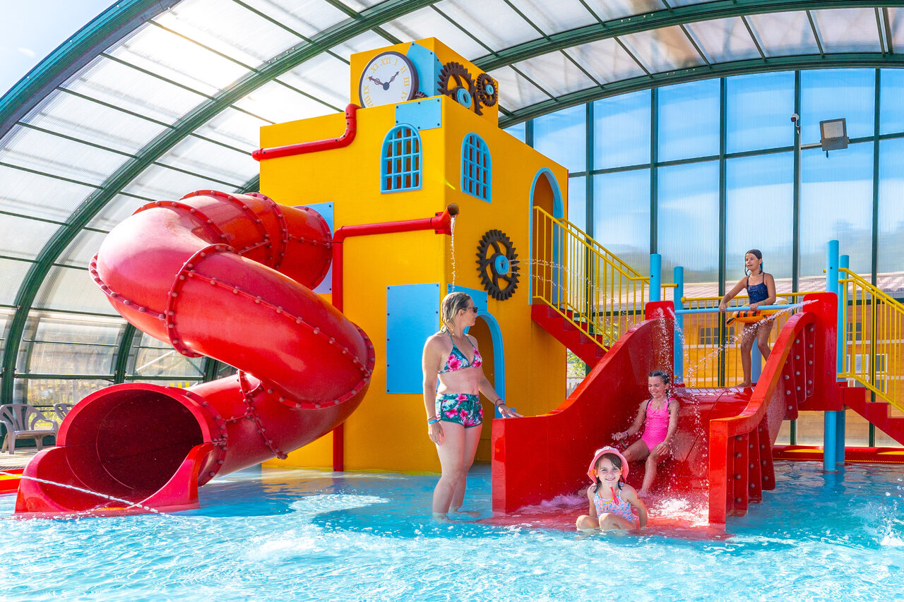 Piscina cubierta con toboganes y juegos de agua en el camping CAPFUN Merle Roux.