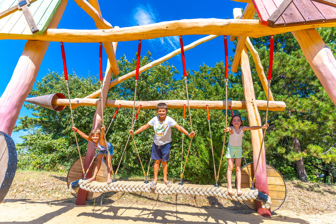 �rea de juegos de madera, ni�os sonrientes en el camping CAPFUN Merle Roux (07).