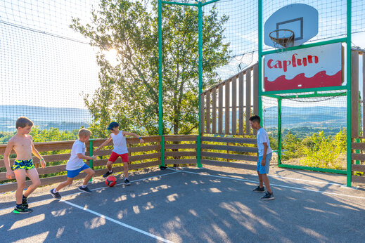 Ni�os jugando f�tbol en campo multideportivo CAPFUN Merle Roux en Baix (07).