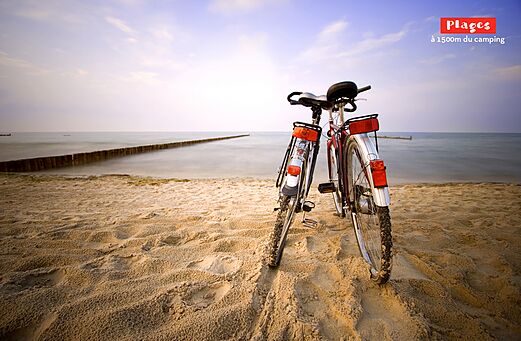 Dos bicicletas en una playa de arena fina cerca del mar en el camping CAPFUN Mer et Soleil en Cap d'Agde (34).
