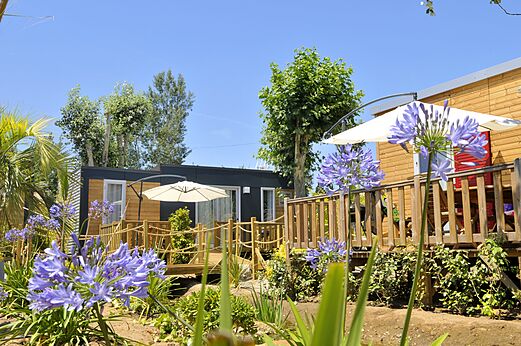 Modernos Mobil-homes con terraza de madera y sombrillas en el camping CAPFUN Mer et Soleil en Cap d'Agde (34).
