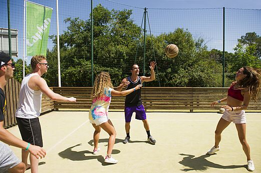 Jóvenes jugando baloncesto en una cancha multideporte en el camping CAPFUN Mer et Soleil en Cap d'Agde (34).