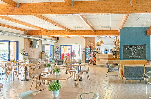 Zona de bar y restaurante moderna con mesas y sillas en el camping VAGUES OCEANES Michelière en Givrand (85).