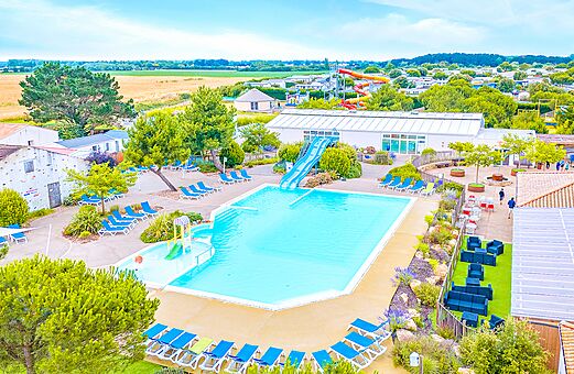 Gran piscina exterior con tobogán y sillas en el camping VAGUES OCEANES Michelière en Givrand (85).