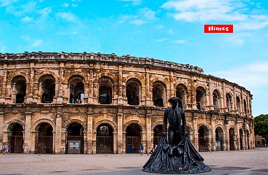 Anfiteatro romano de Nimes y estatua de torero, lugar para visitar en Occitania.
