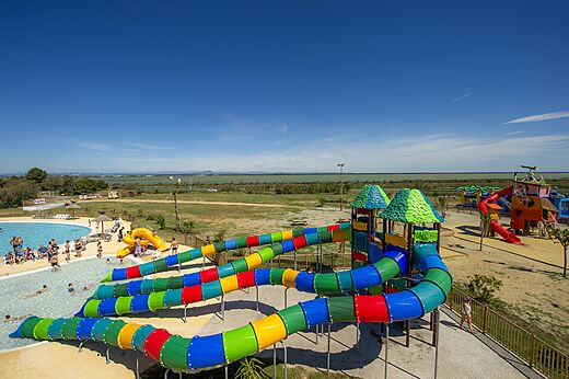 Toboganes acuáticos coloridos y piscina exterior en el camping CAPFUN Mille Pépites en Carnon (34).