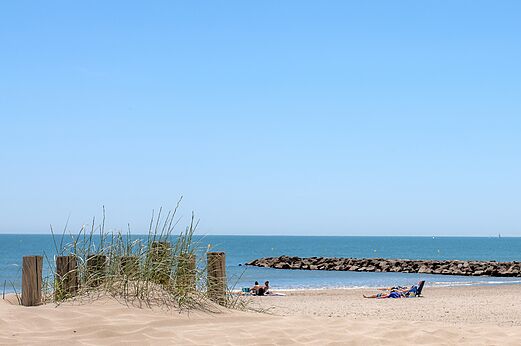 Playa de arena, mar y dique rocoso en el camping CAPFUN Mille P�pites en Carnon (34).