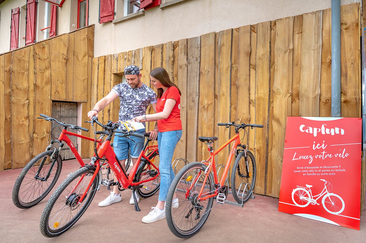 Pareja alquilando bicicletas rojas en el camping CAPFUN Mirabelle en VOLSTROFF (57).