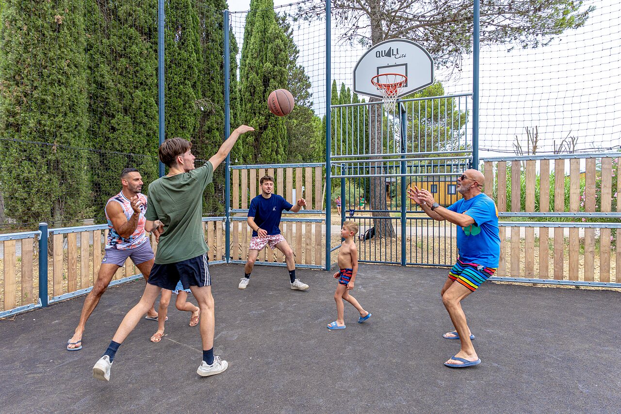 Cancha de baloncesto con familia jugando, ambiente divertido en el camping VAGUES OCEANES Monte Cristo en Vauvert (30).