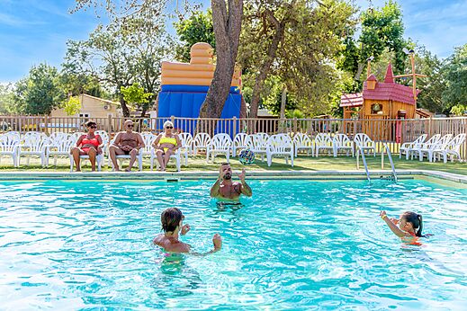 Piscina exterior, bañistas y juegos inflables en el camping VAGUES OCEANES Monte Cristo en Vauvert (30).