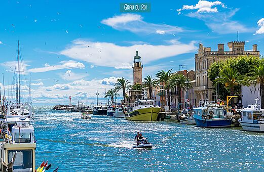 Puerto animado de Grau du Roi con barcos, moto acuática y faro, Occitania.