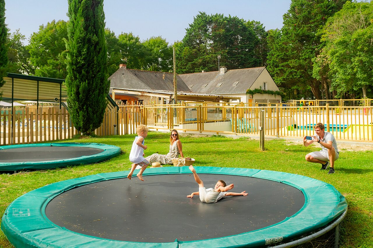 Ni�os saltando en trampolines, piscina cercana, camping CAPFUN Montsabert, COUTURES (49).