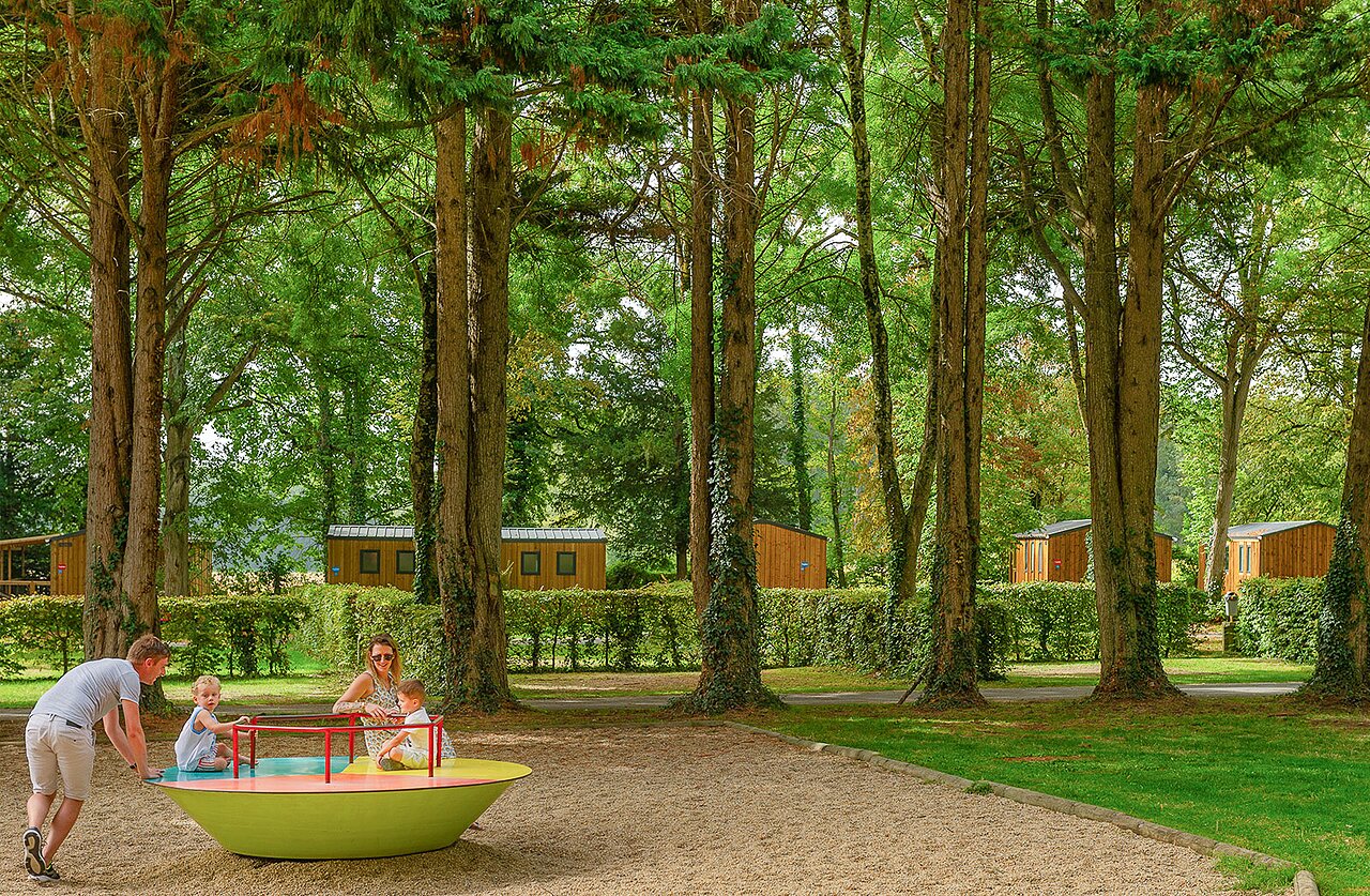 Familia jugando en carrusel colorido, Mobil-homes en el camping CAPFUN Montsabert en COUTURES (49).