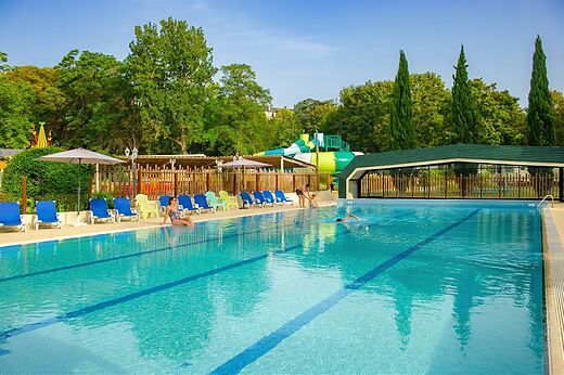 Piscina exterior con tobogán acuático y sillas en el camping CAPFUN Montsabert en COUTURES (49).