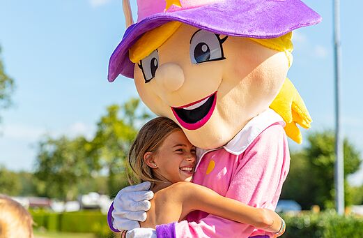 Mascota del camping y niña sonriente abrazándose, animación en el camping CAPFUN Montsabert en COUTURES (49).