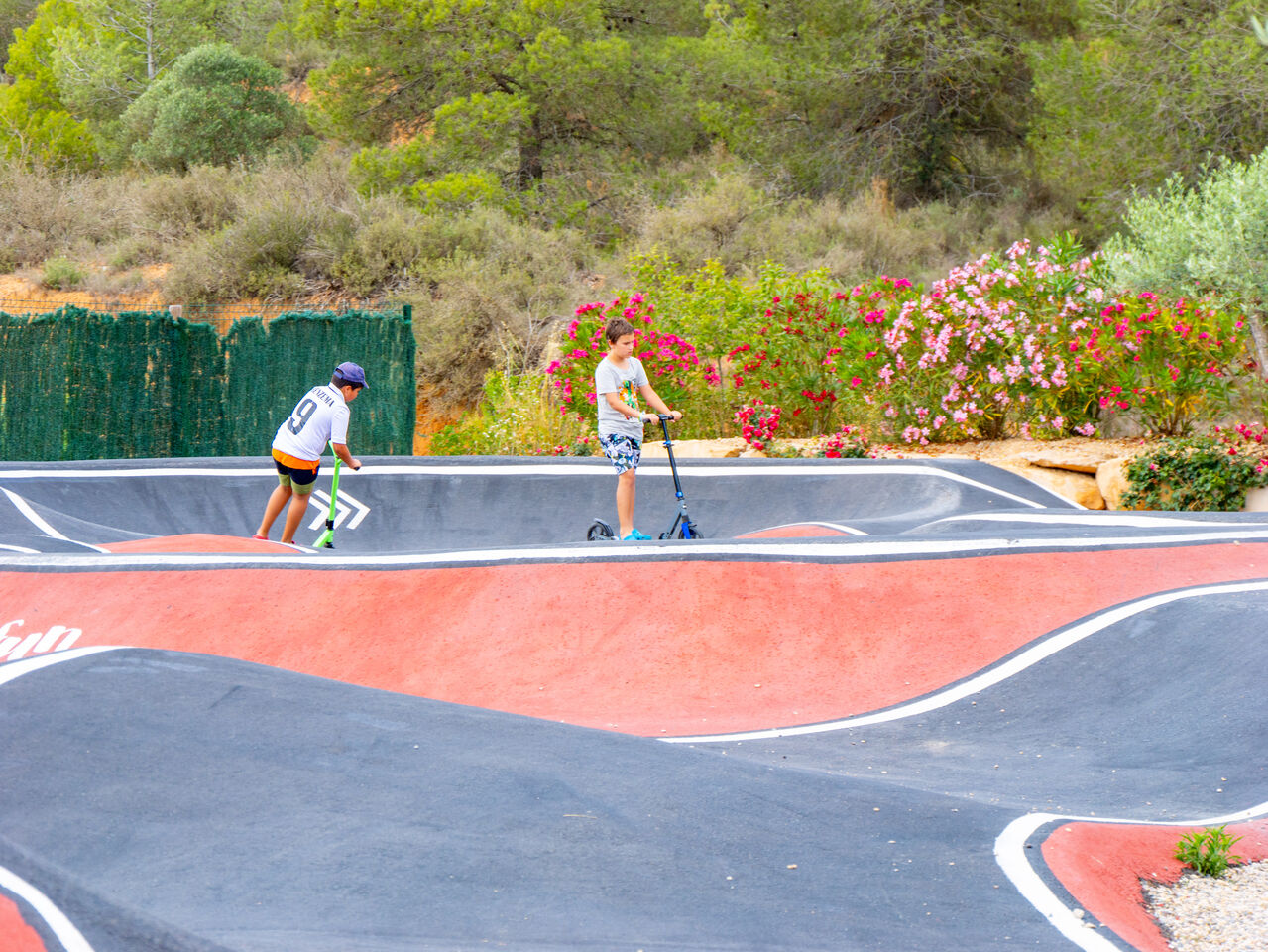 Pista de pump track con ni�os en patinete en el camping CAPFUN Montblanc Park en Montblanc (43).