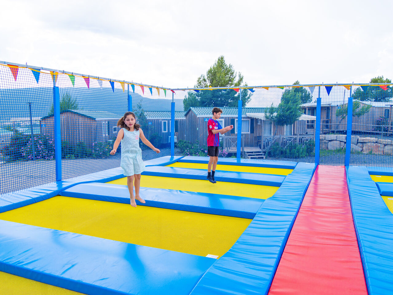 Ni�os divirti�ndose en trampolines, Mobil-homes al fondo en camping CAPFUN Montblanc Park en Montblanc (43).