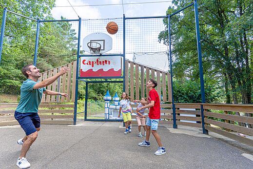 Cancha de baloncesto exterior con jugadores en el camping CAPFUN Moulinal en BIRON (24).