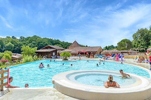 Gran piscina exterior con jacuzzi y bañistas en el camping CAPFUN Moulinal en BIRON (24).