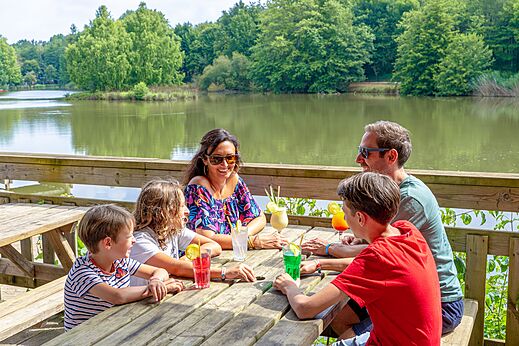 Familia sonriente bebiendo c�cteles en terraza junto al lago en el camping CAPFUN Moulinal en BIRON (24).