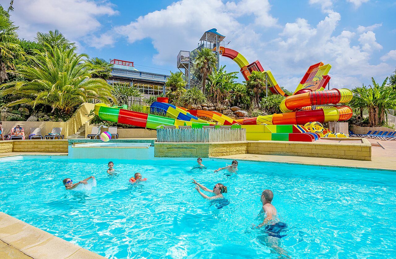 Piscina exterior con toboganes acu�ticos coloridos y familias en el camping VAGUES OCEANES Moulin de Cadillac en Noyal-Muzillac (56).