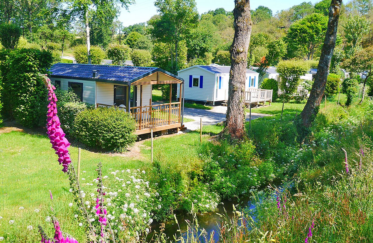 Mobil-homes con terrazas de madera y arroyo en el camping VAGUES OCEANES Moulin de Cadillac en Noyal-Muzillac (56).
