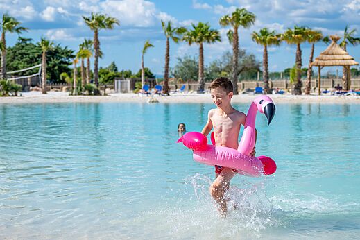 Piscina, niño con flotador flamenco en el camping CAPFUN La Nautique en Narbonne.