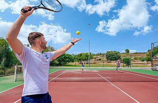 Jugador de tenis sacando en pista exterior al camping CAPFUN La Nautique en Narbonne (11).