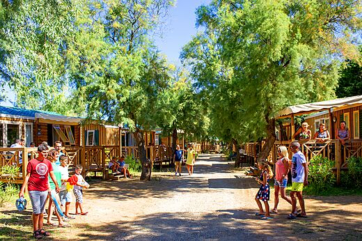 Calle sombreada con Mobil-homes y veraneantes en el camping CAPFUN La Nina en Agde (34).