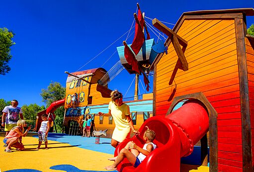 Gran parque infantil con forma de barco pirata y toboganes en el camping CAPFUN La Nina en Agde (34).