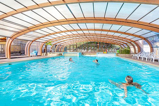 Piscina cubierta climatizada con bañistas y sillas en el camping VAGUES OCEANES Odyssée en Villers sur mer (14).