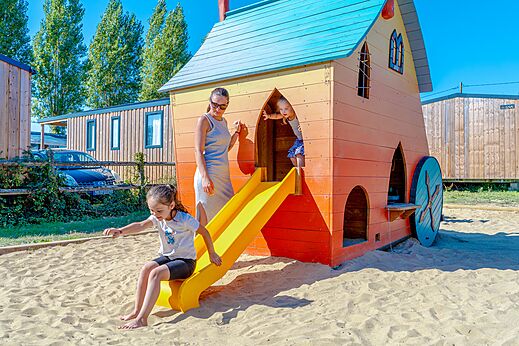 Zona de juegos con casita y tobogán para niños en el camping VAGUES OCEANES Odyssée en Villers sur mer (14).