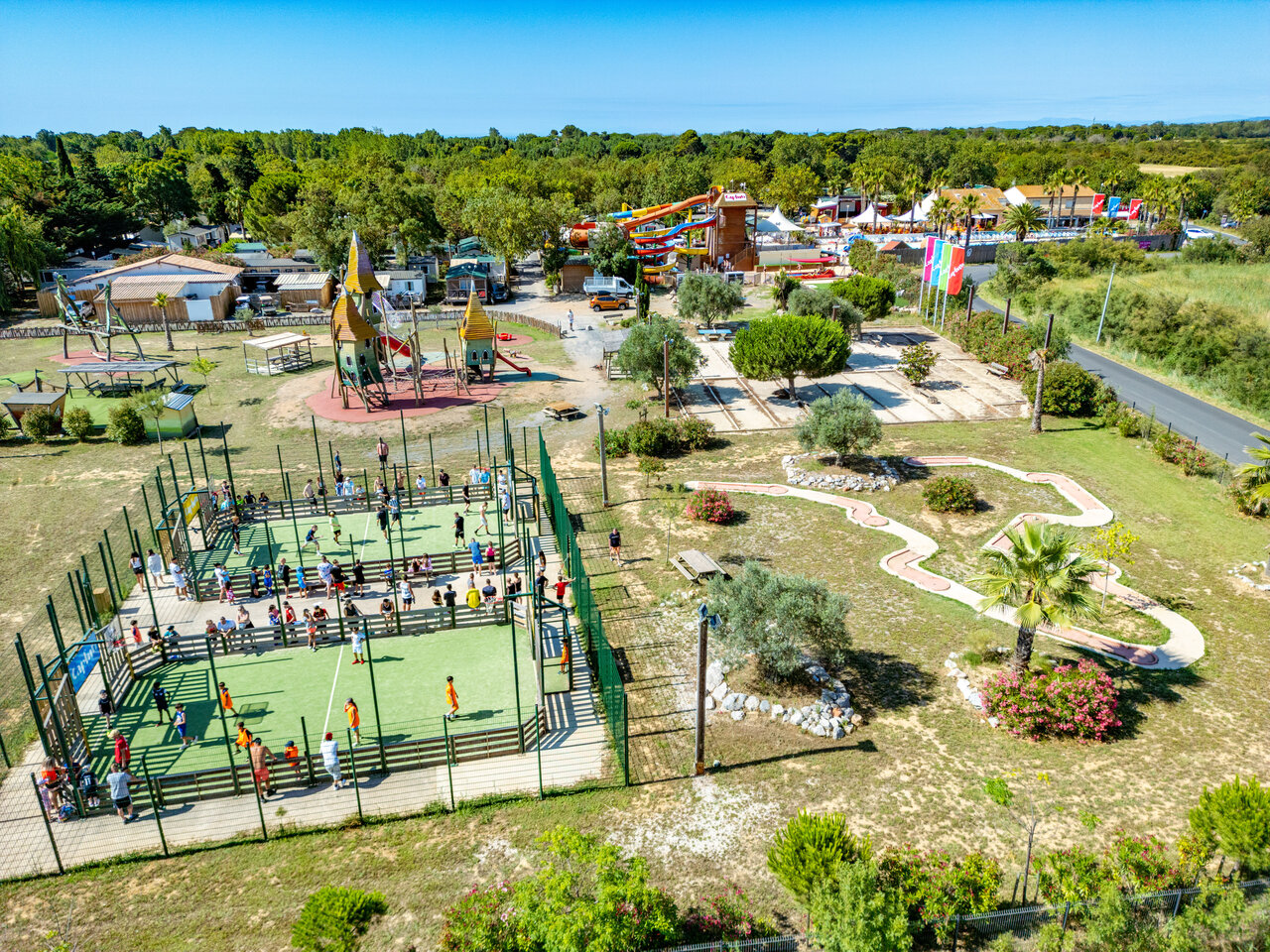 Pista multideporte con jugadores, parque infantil, minigolf en camping CAPFUN Ondines en Vias Plage (34).