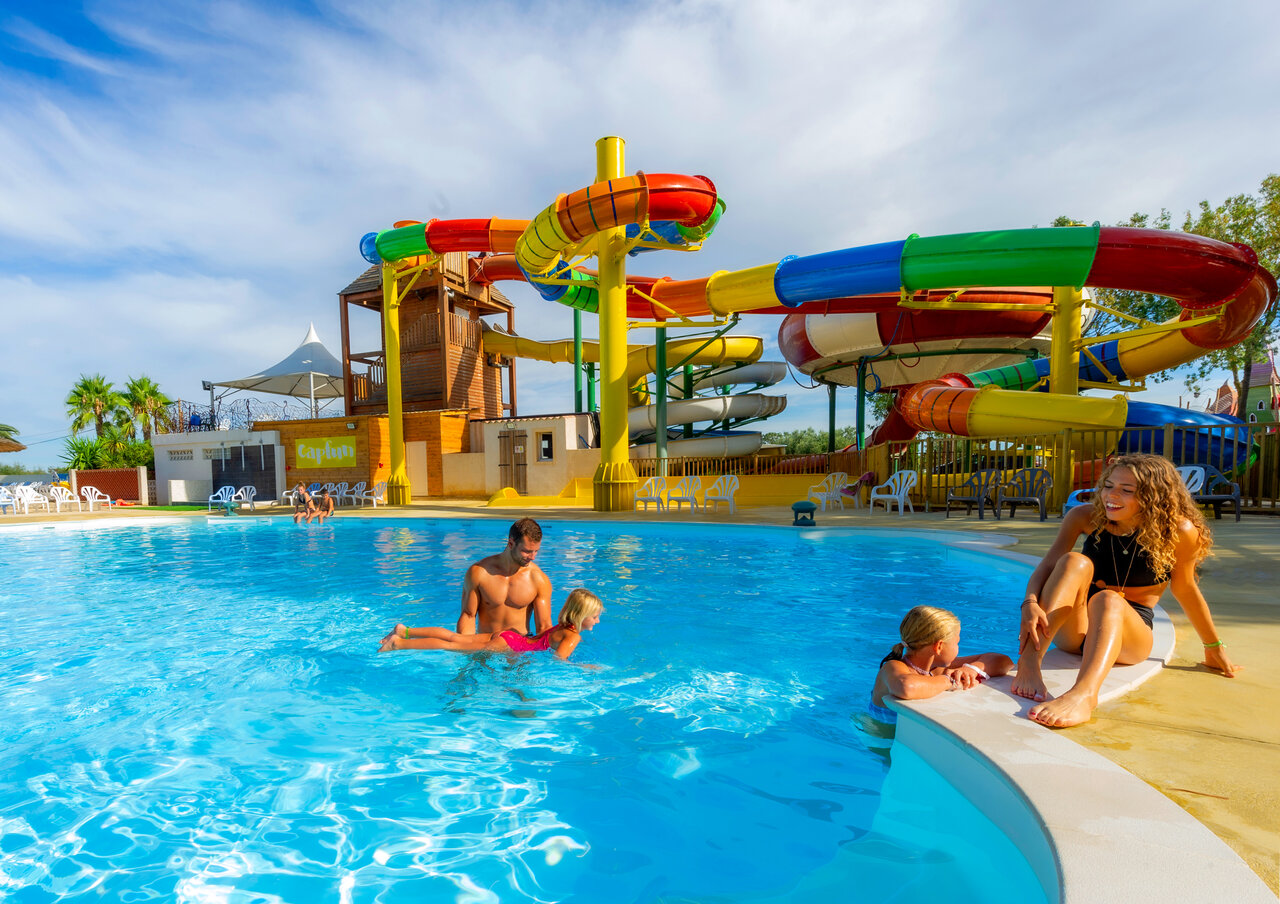 Piscina exterior, toboganes acu�ticos coloridos, familia en el camping CAPFUN Ondines en Vias Plage (34).