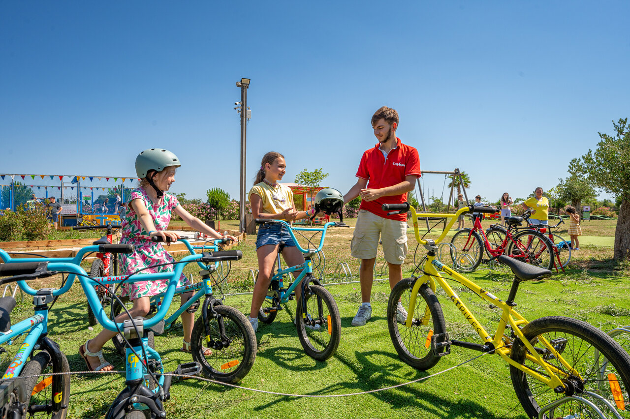 Ni�os y animador con bicicletas y cascos para actividad en camping CAPFUN Ondines en Vias Plage.