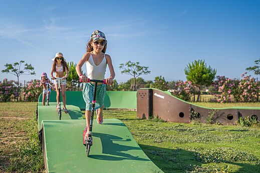 Niñas en patinetes en una pista de pump track en el camping CAPFUN Ondines en Vias Plage (34).