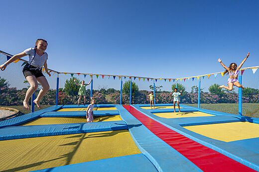 Zona de juegos con trampolines y niños saltando en el camping CAPFUN Ondines en Vias Plage (34).