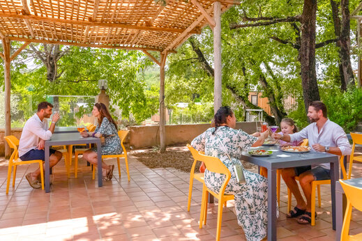 Familias y parejas cenando en la terraza sombreada del restaurante en el camping CLICOCHIC Orée d'Azur en OPIO (06).