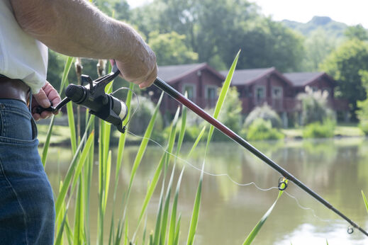 Pescador con caña y carrete junto al lago en el camping CAPFUN UK Otter Falls en Upottery Nr Honiton.