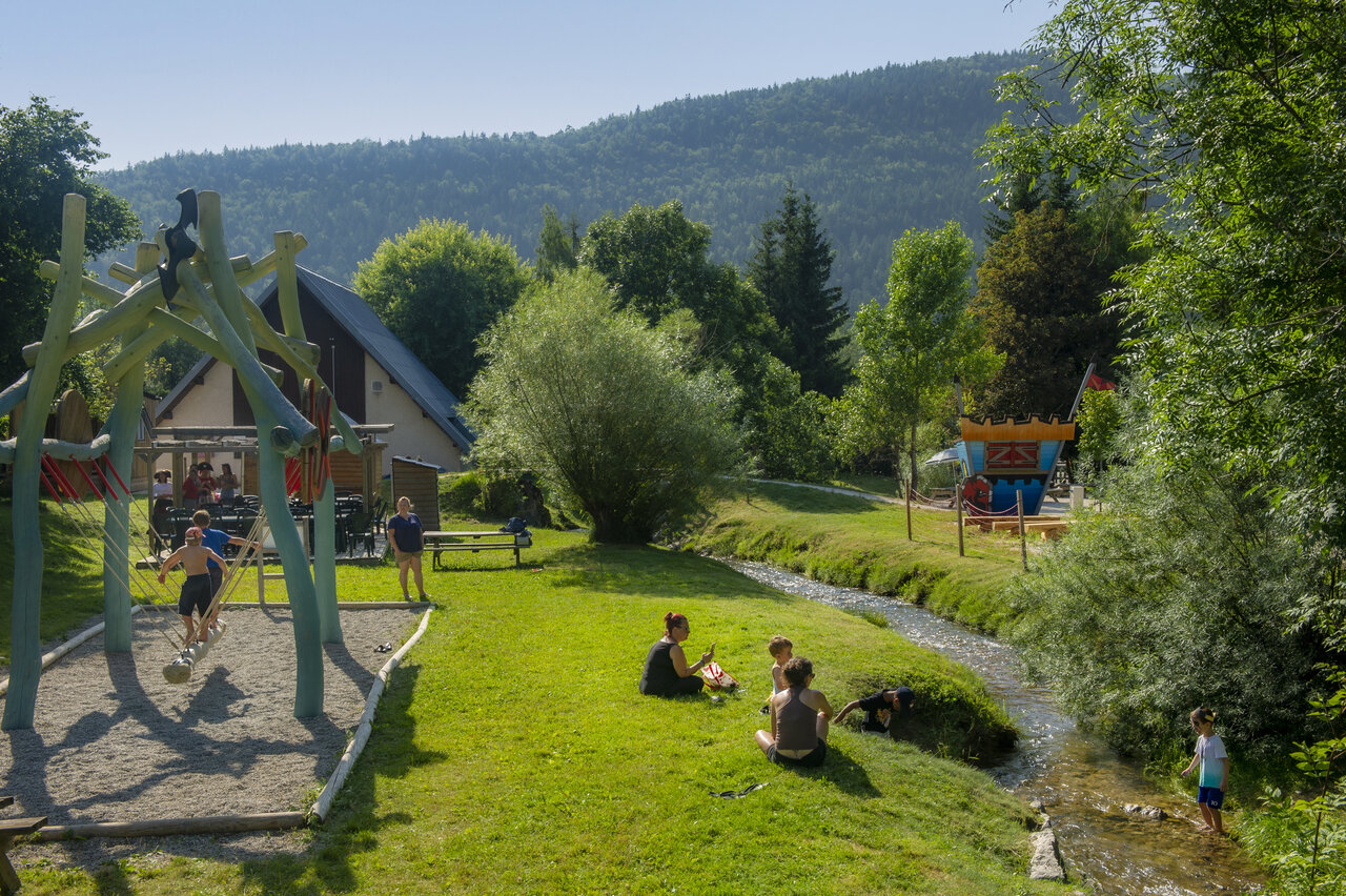 Zona de juegos infantil, arroyo y naturaleza en el camping CAPFUN Oursi�re en Villard de Lans (38).